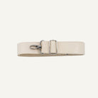 A light beige leather belt with a silver-tone metal buckle and swivel clip, laid flat on a light gray background.
