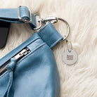 Blue leather bag with a keychain on a white fur surface