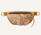 A handmade furred waist bag featuring a textured, layered patchwork design in shades of brown and beige, finished with a tan leather zipper trim and brass hardware rings on a white background.